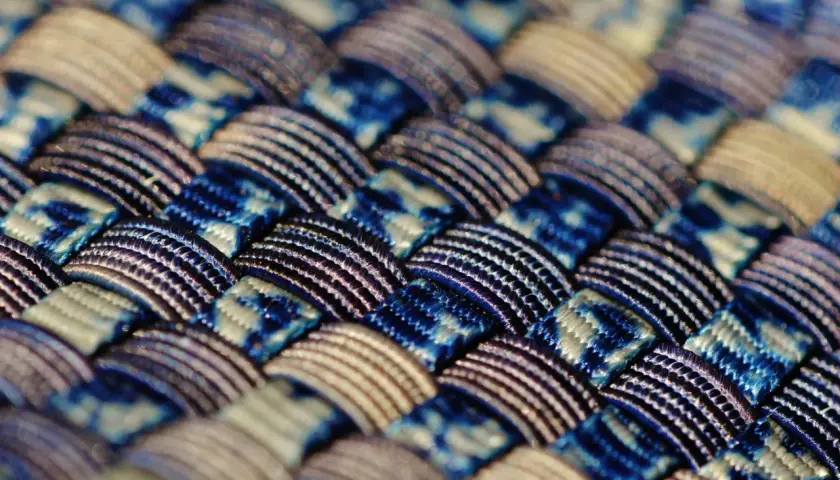 Gros plan sur un tissu intelligent aux motifs bleus et blancs entrelacés, révélant une texture complexe et des fils brillants.