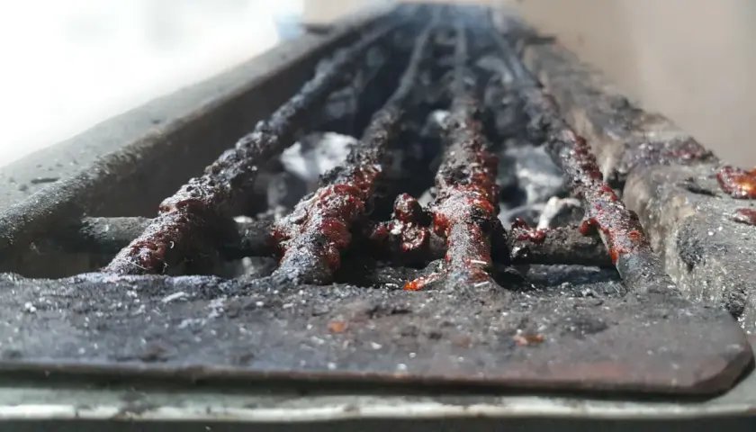 Grille de barbecue à charbon très sale, couverte de résidus de cuisson. Il est temps de nettoyer ce barbecue charbon pour la prochaine utilisation.
