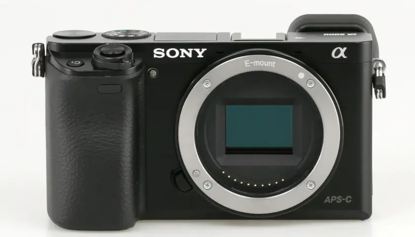 Czarny aparat Sony a6000, gotowy do testów. Widoczny obiektyw E-mount i sensor APS-C.