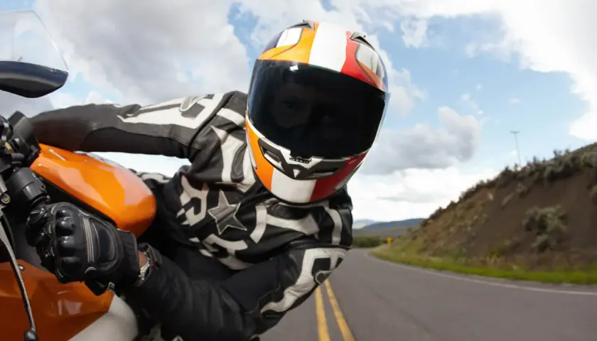 Motociclista con casco y visera oscura, listo para una multa por exceso de velocidad en la carretera.