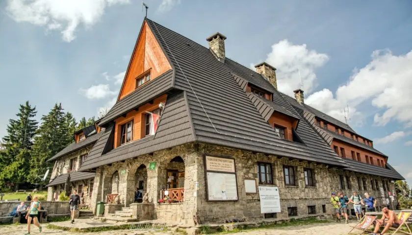 Schronisko PTTK na Turbaczu, popularne wśród turystów z Nowego Targu, z kamienną fasadą i drewnianymi elementami.