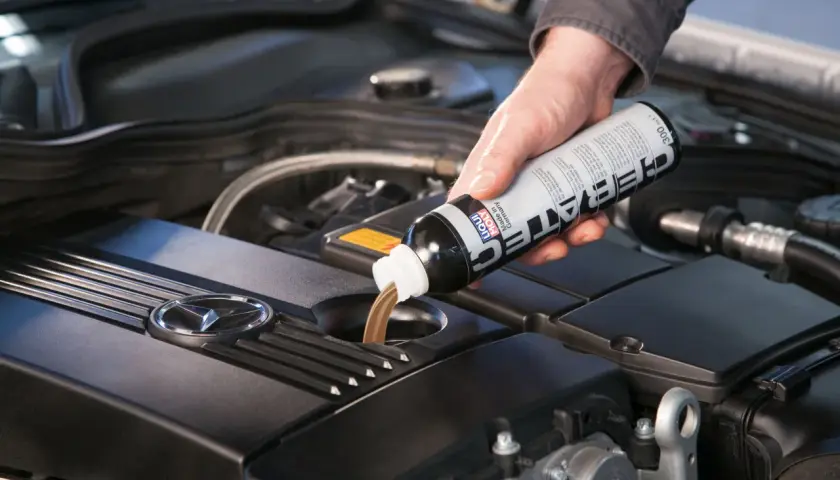 Dłoń wlewa płyn spulung liqui moly do silnika samochodu.