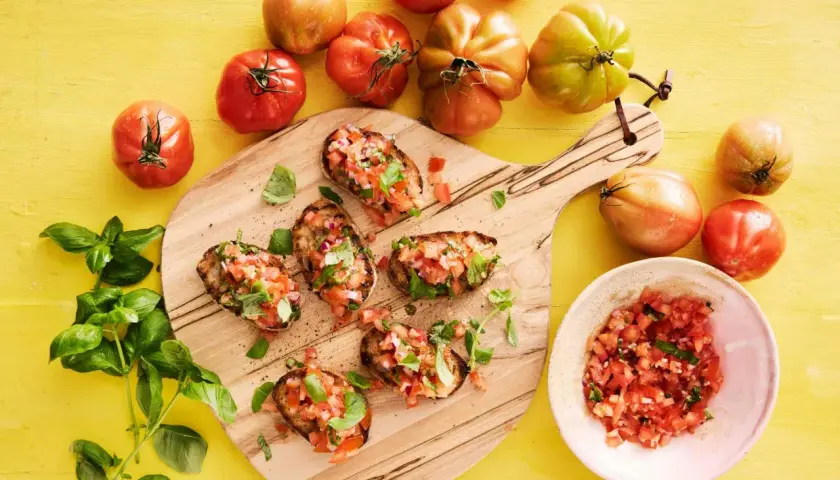 Färska tomater och basilika toppar rostat bröd, en perfekt start för ett enkelt bruschetta recept.