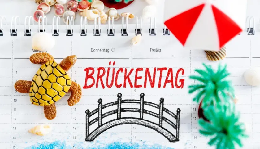 Urlaubsplanung 2026: Ein Brückentag mit Schildkröte, Brücke und Muscheln lädt zum Träumen ein.