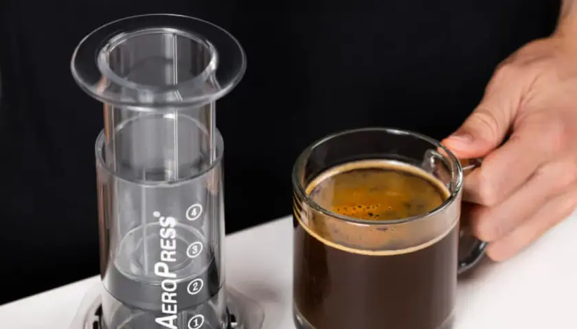 AeroPress gotowy do zaparzenia idealnego espresso. Obok filiżanka aromatycznej kawy.