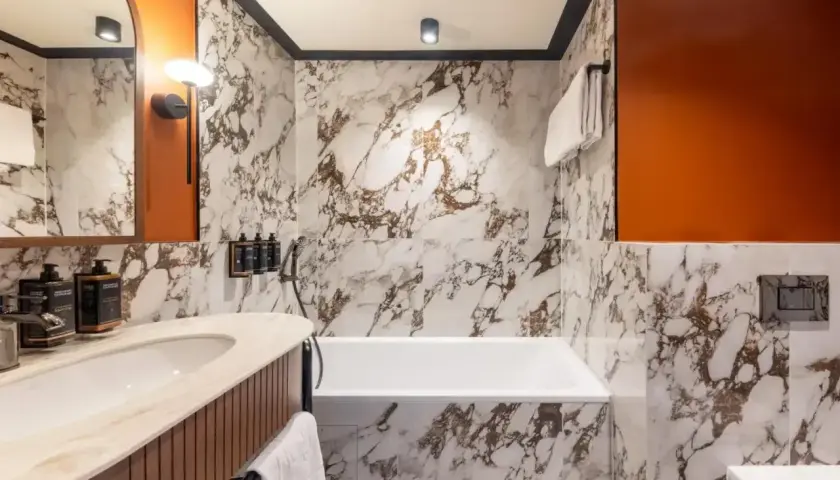 Elegancka łazienka w hotelu Mercure Gdynia z marmurowymi płytkami, wanną i umywalką.