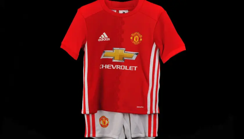 Dziecięcy komplet piłkarski Manchester United: czerwona koszulka i białe spodenki.
