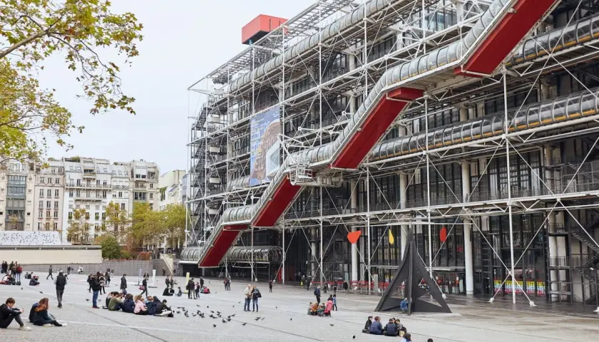 Centrum Pompidou w Paryżu z czerwonymi schodami ruchomymi i ludźmi na placu.