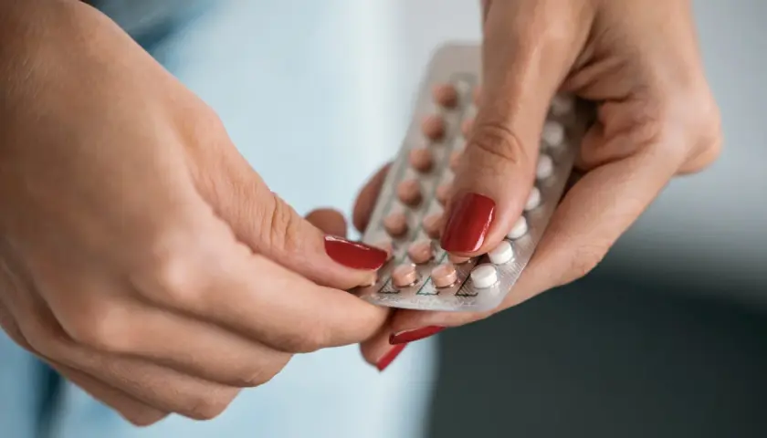 Hände halten eine Blisterpackung mit Pillen, darunter eine Drospirenon Pille.