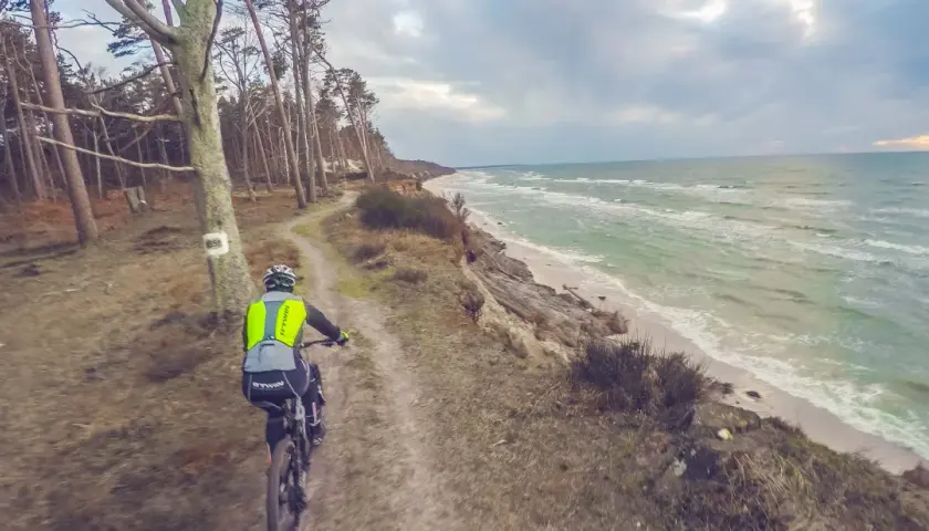 Rowerzysta na ścieżce przy klifie, w tle morze. Trasa rowerowa w okolicach Słupska.