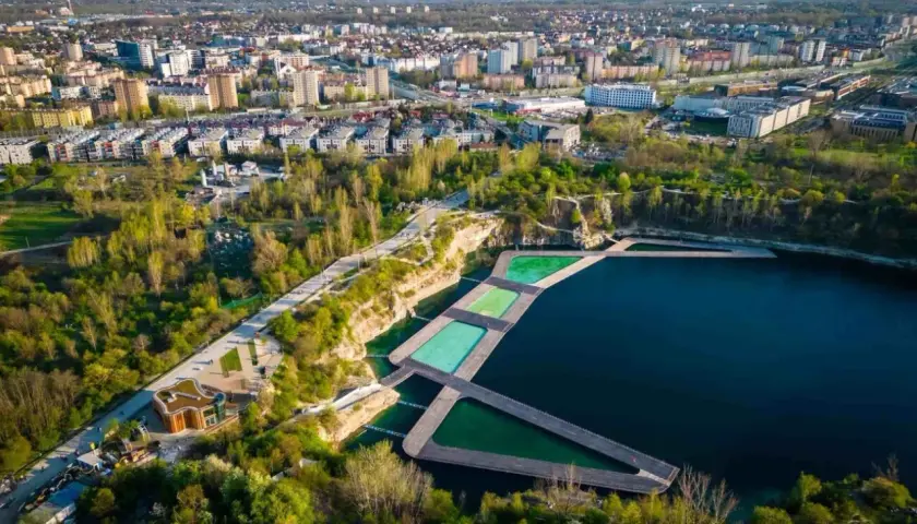 Widok na Zakrzówek Kraków kąpielisko z drewnianymi pomostami i basenami w otoczeniu zieleni i zabudowy miejskiej.