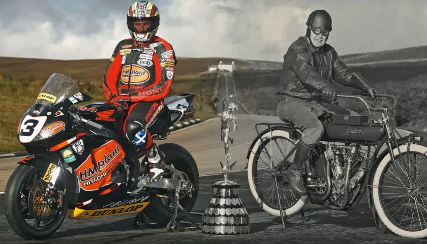 Conor Cummins junto a su moto de carreras y un trofeo, junto a un piloto histórico en una Indian.