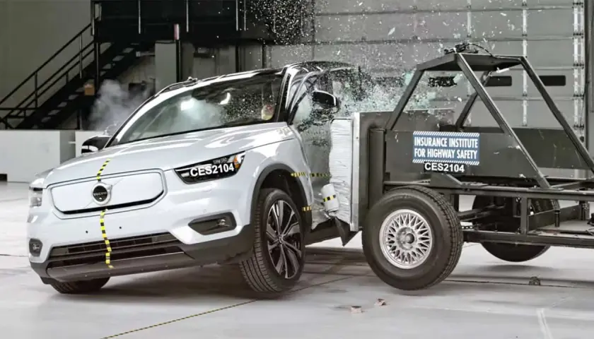 En vit Volvo XC40 krocktestas mot en barriär. Glas splittras och bilen deformeras vid kollisionen.