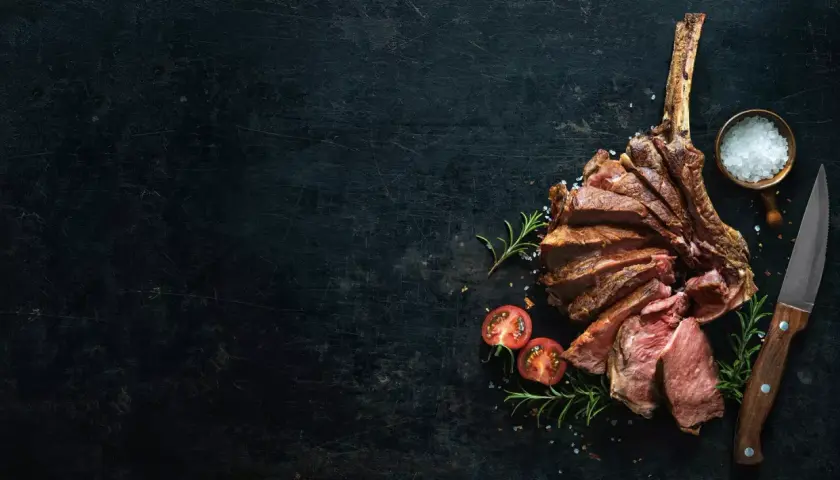 Côte de bœuf tranchée, saignant, avec une texture bleu parfaite. Sel, romarin et tomates cerises accompagnent ce plat.