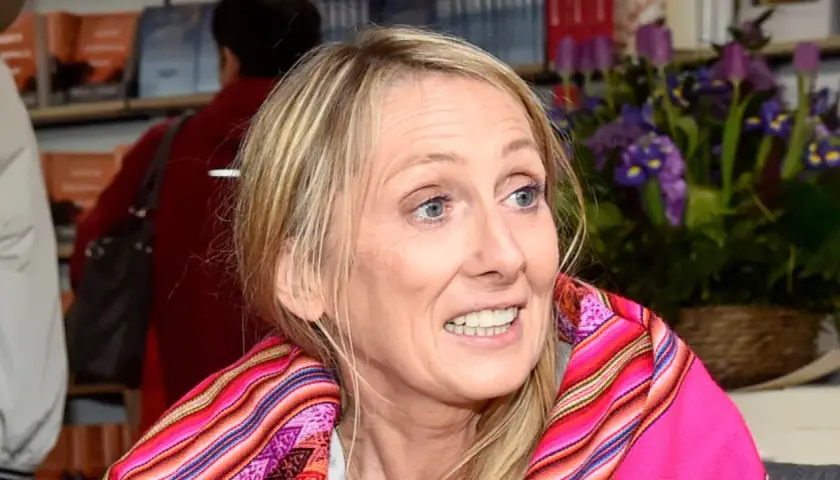 Beata Pawlikowska z kolorowym szalem na tle książek i kwiatów.
