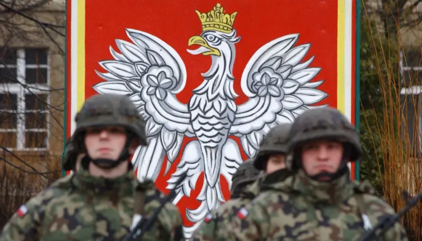 Żołnierze w mundurach stoją przed godłem Polski. Dowódca kompanii, stopień wojskowy, jest gotowy do akcji.