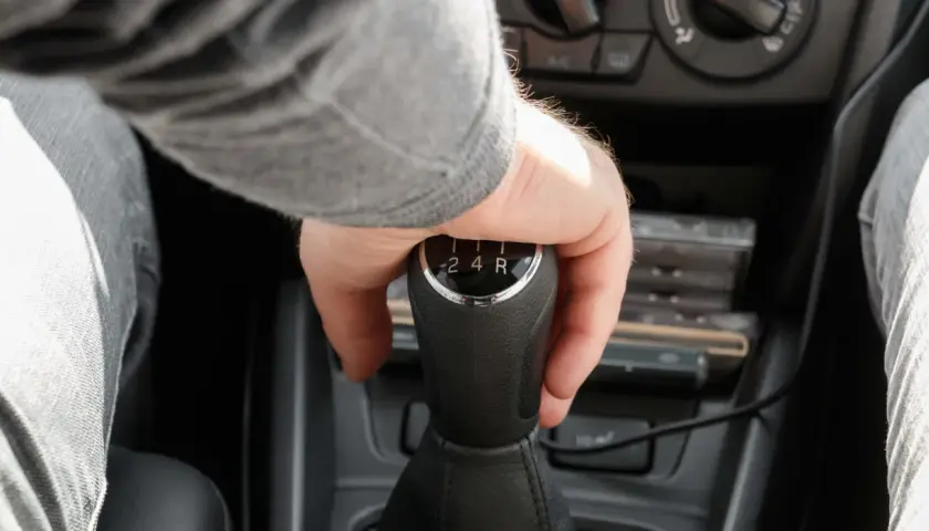 Mano cambiando de marcha en un coche, se escucha un ruido al girar el volante en movimiento a la derecha.