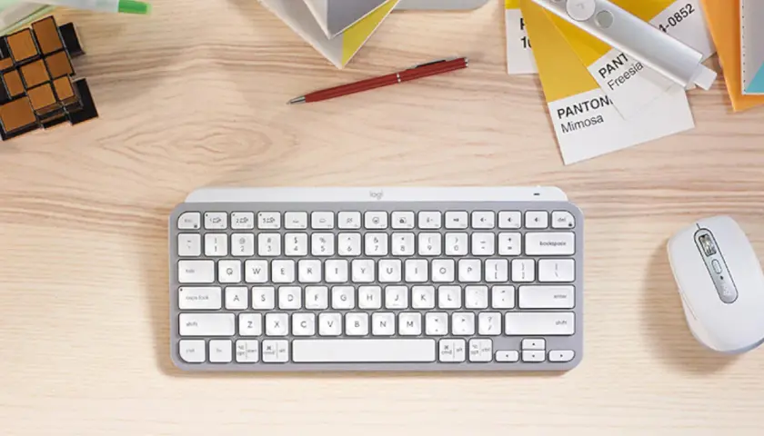 Escritorio con varios tipos de teclado, ratón, bolígrafo, cubos y muestras de color Pantone.