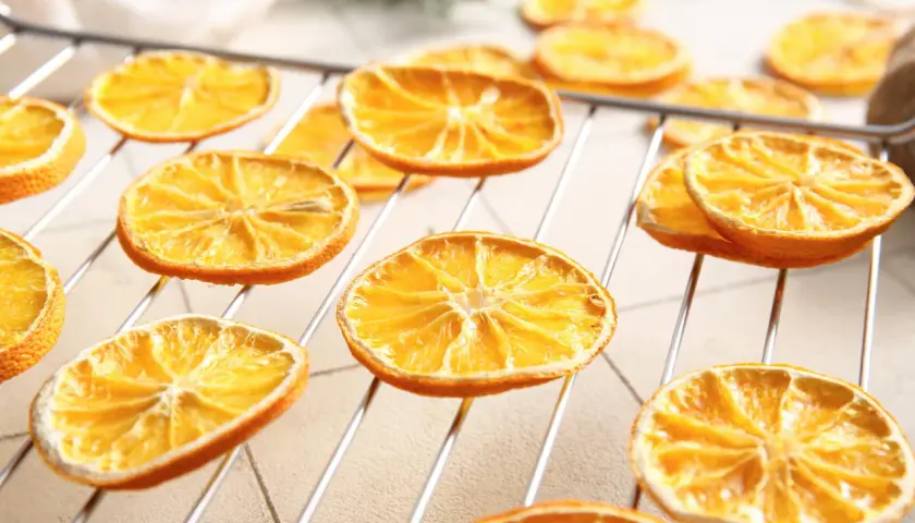 Getrocknete Orangenscheiben auf einem Rost, bereit zum Trocknen. So trocknet man Orangenscheiben für Dekorationen oder zum Verzehr.