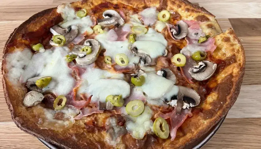 Chrupiący spód do pizzy z pieczarkami, szynką i oliwkami, polany ciągnącym się serem.