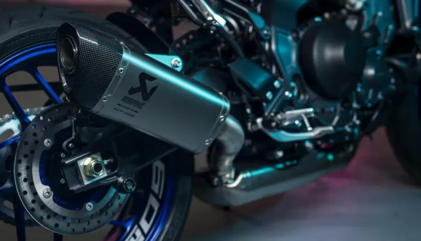 Wydech Akrapovič na motocyklu Yamaha MT-09, z karbonową końcówką i niebieskimi detalami felgi.