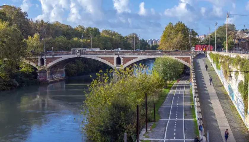 Il ponte nuovo di Roma attraversa il Tevere, con una pista ciclabile e pedonale lungo la riva.