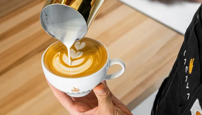 Barista tworzy latte art, wlewając spienione mleko do kawy. To świetny pomysł na to, co zamiast mleka do kawy, gdy szukasz czegoś innego.