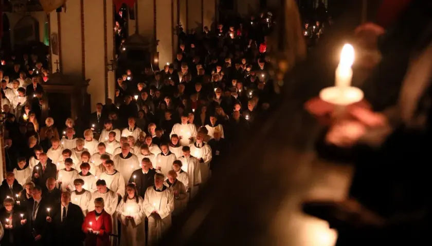 Uczestnicy niosący świece w kościele podczas Wigilii Paschalnej. Długość nabożeństwa jest różna, ale atmosfera jest podniosła.