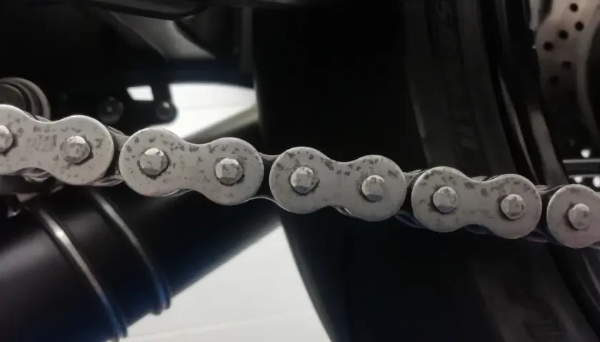 La catena di una moto mostra segni di ruggine, indicando la necessità di manutenzione.