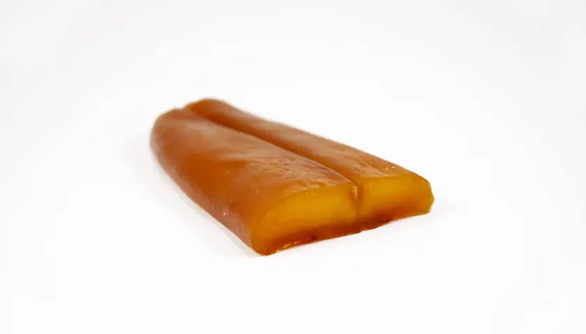 Zwei goldbraune, längliche Stücke Bottarga di Muggine liegen nebeneinander auf weißem Grund.