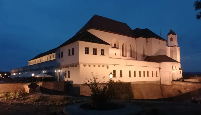 Brno zamek nocą, oświetlony, z wieżą i murami obronnymi.