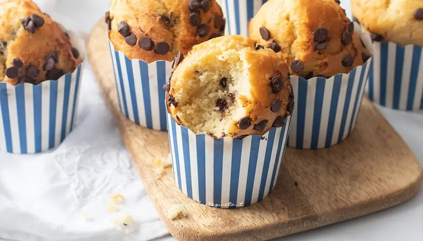 Muffin in friggitrice ad aria con gocce di cioccolato, uno è stato morso rivelando un interno soffice e goloso.