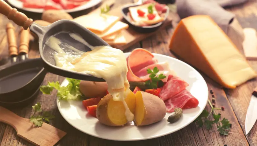 Raclette, le meilleur plat français, avec pommes de terre, charcuterie et fromage fondu. Un délice réconfortant.
