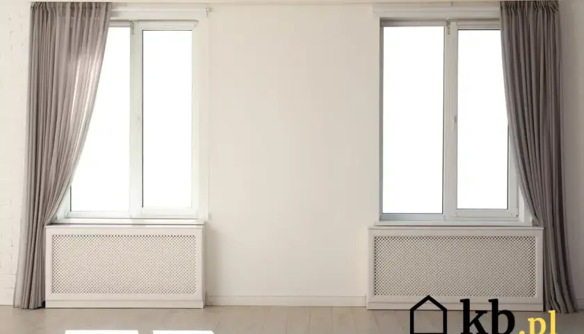 Nowoczesna osłona na stary kaloryfer pod oknem, z szarymi zasłonami po bokach.