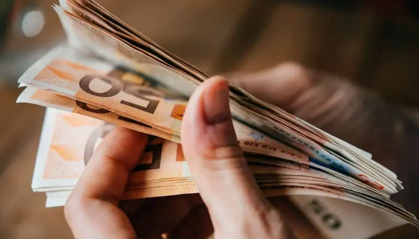 Hände halten einen Stapel Euro-Scheine. Dies könnte relevant sein für den **privatinsolvenz freibetrag**.