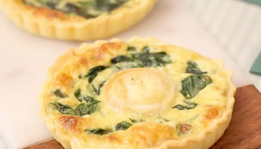 Une délicieuse quiche épinard chèvre, dorée et appétissante, avec une touche de fromage de chèvre au centre.