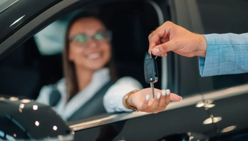Kluczyki do nowego auta przekazuje uśmiechnięta kobieta, która skorzystała z oferty mbank leasing.