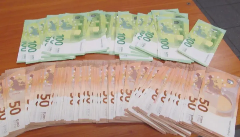Duże stosy banknotów 100 i 50 euro leżą na drewnianym stole. Zastanawiasz się, ile gotówki można przewozić samolotem?