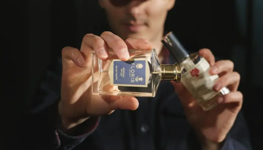 Mężczyzna trzyma perfumy Floris Special No 127. W składzie może być benzoesan benzylu, nadający zapachowi głębi.