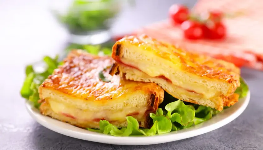 Deux croque monsieur gourmands, comme ceux de grand-mère, servis sur un lit de salade verte. Le fromage fondant et le pain doré donnent envie.