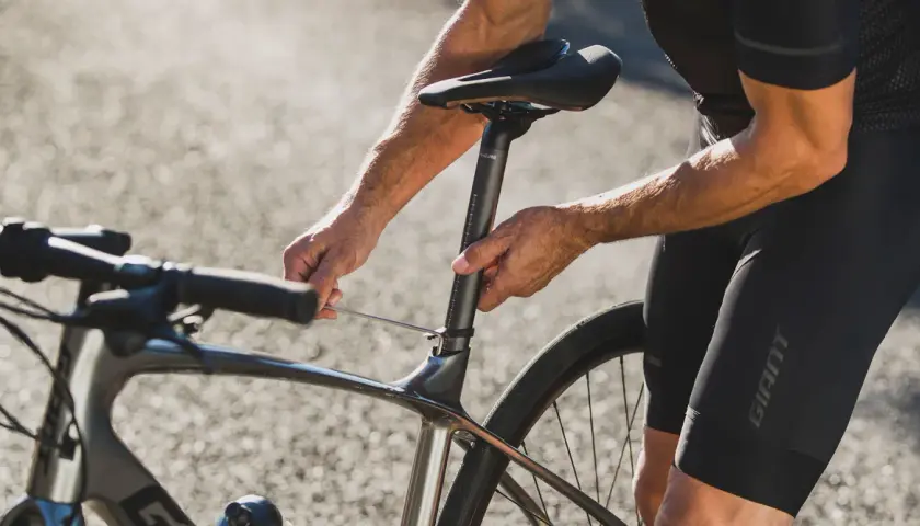 Rowerzysta reguluje wysokość siodełka, by uzyskać optymalną pozycję na rowerze szosowym.
