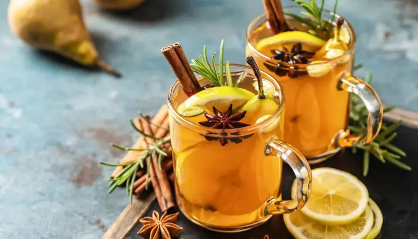 Due bicchieri di hot toddy ricetta con cannella, anice stellato, limone e pera. Perfetto per scaldarsi.