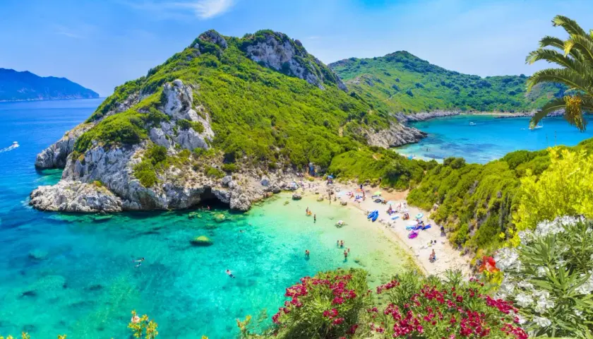 Malownicza zatoka z turkusową wodą i piaszczystą plażą. W maju Grecja zachwyca zielenią i kwitnącymi kwiatami.