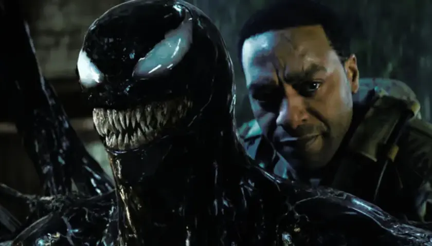 Venom, le symbiote noir aux dents acérées, se rapproche d'un homme au regard intense. Une scène prometteuse pour Venom 3.