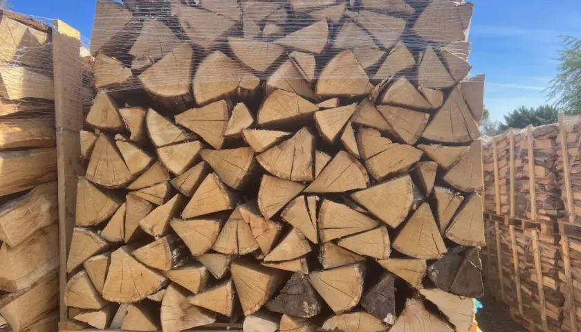 Un grand stère de bois, bien empilé et emballé sous plastique, prêt pour l'hiver.