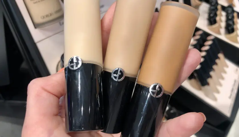 En hand håller tre flaskor Giorgio Armani foundation i olika nyanser.