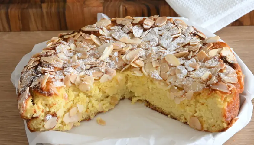 Delizioso dolce senza glutine con mandorle a lamelle e zucchero a velo, su un piatto bianco.