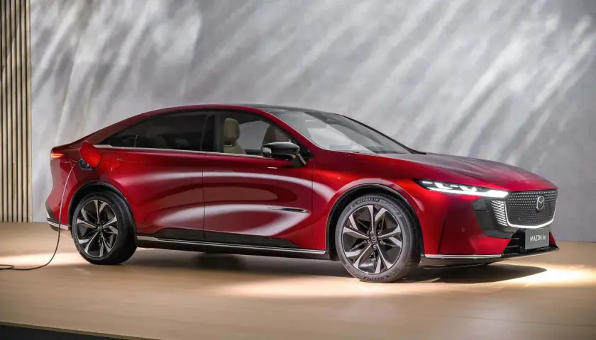 Czerwona Mazda 6e, ładowana elektrycznie, prezentuje nowoczesny design z eleganckimi liniami i dynamicznym profilem.