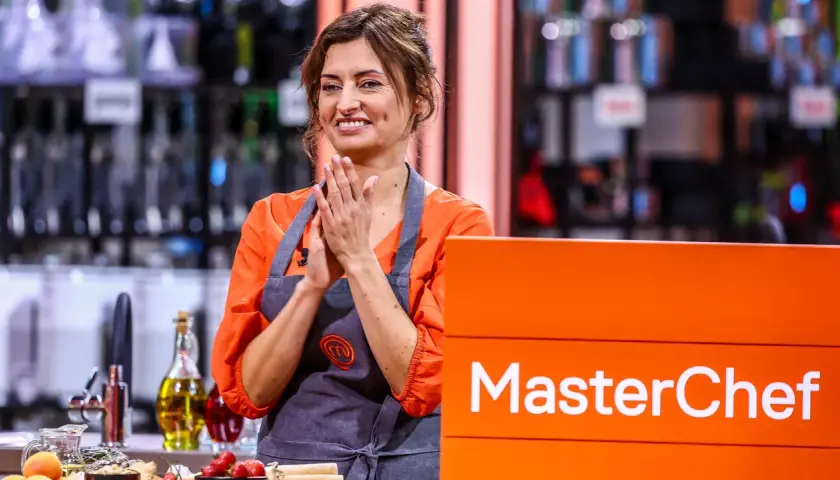Barbara Tomkowiak w fartuchu MasterChef, z dłońmi złożonymi w geście radości.
