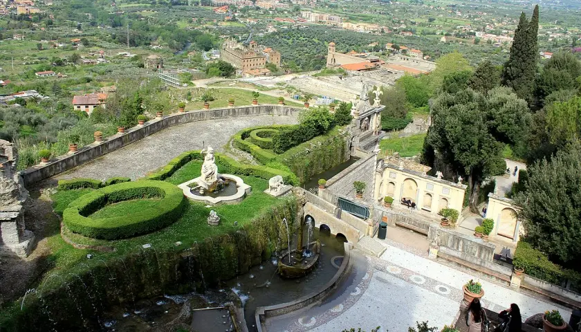 Vue panoramique de la Villa d'Este, avec ses jardins en terrasse, ses fontaines et sa statue, dominant la campagne environnante.